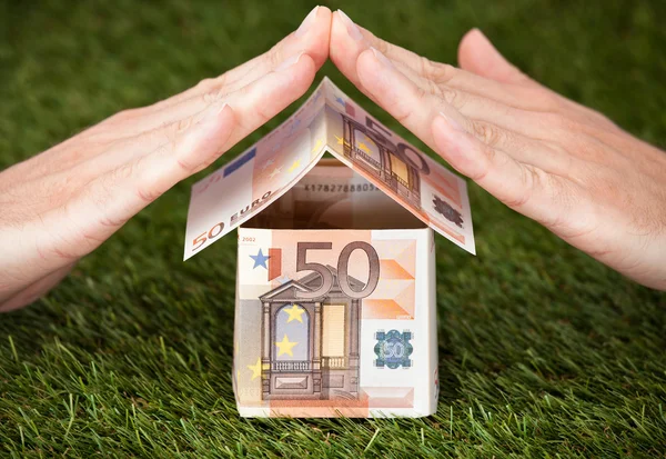 Geschäftsmann schützt Euro-Haus auf Grünland — Stockfoto