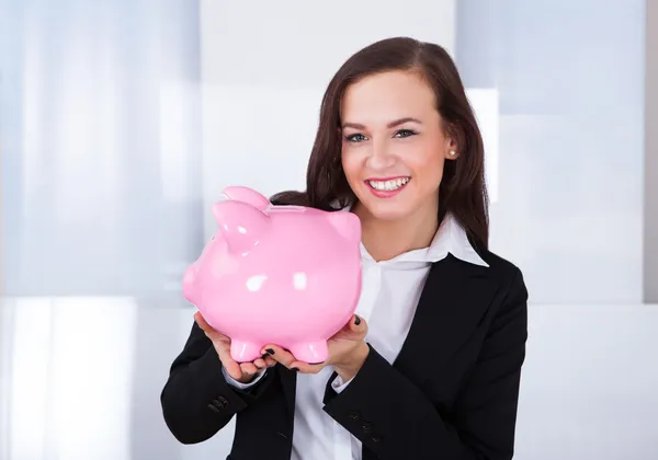 Empresária segurando banco porquinho — Fotografia de Stock