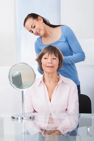 Cuidador peinando el cabello de la mujer mayor — Foto de Stock