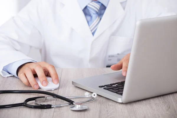 Midsection Of Doctor Using Laptop And Mouse At Desk — Stock Photo, Image