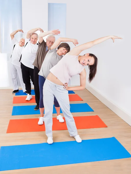 Entrenador y clientes mayores haciendo ejercicio de estiramiento — Foto de Stock