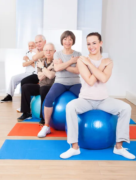 Tränare och senior kunder sitter på fitness bollar — Stockfoto