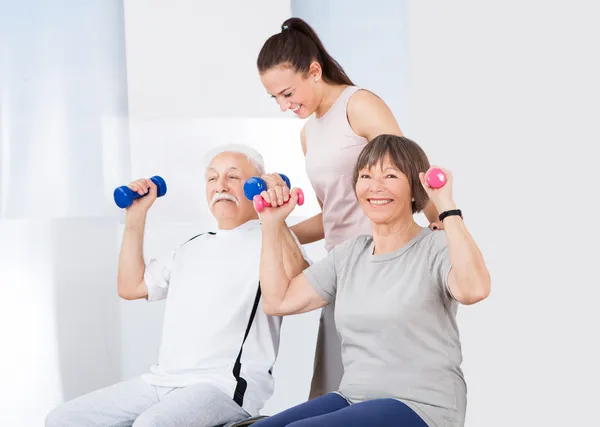 Trainer hilft Senioren-Paar mit Hanteln — Stockfoto