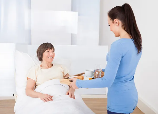 Badante che serve la prima colazione alla donna anziana — Foto Stock