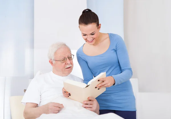 Conciërge en senior man boek lezen — Stockfoto