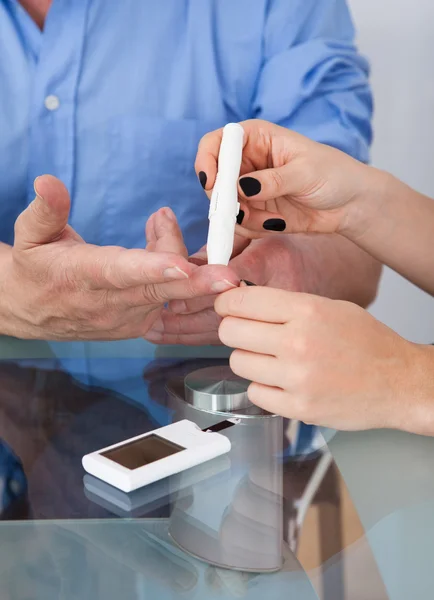 Médico revisando el nivel de glucosa en el paciente diabético — Foto de Stock