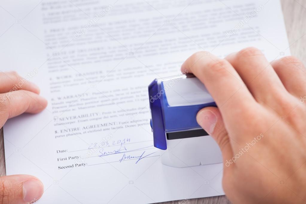 Businessman Stamping Contract Paper On Table