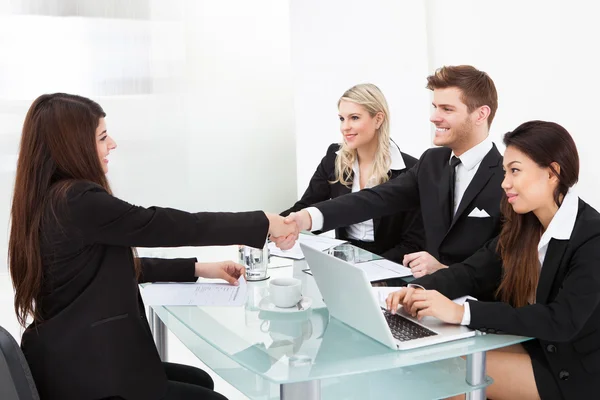 Colleagues Shaking Hands At Desk — Stock Photo, Image