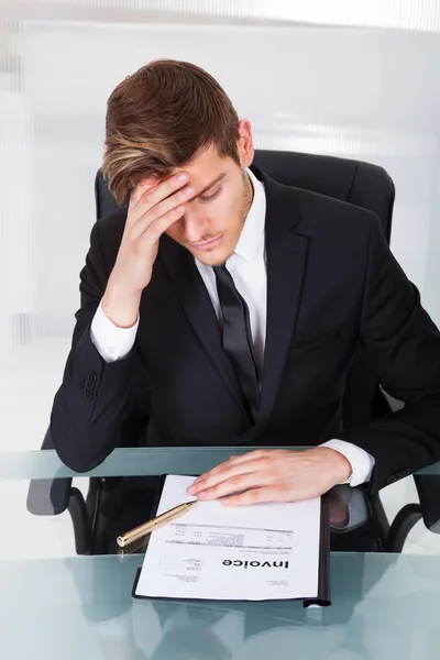 Empresario cansado con factura en el escritorio — Foto de Stock