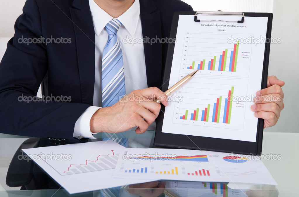 Confident Businessman Showing Graphs In Office