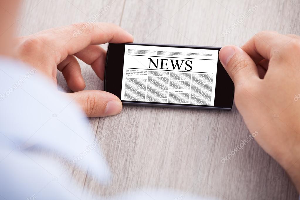 Businessman Surfing News On Smartphone At Desk