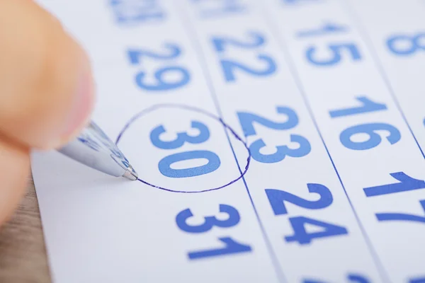 Geschäftsmann markiert Datum auf Kalender am Schreibtisch — Stockfoto