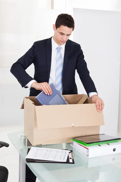 Бизнесмен упаковывает файлы в картонную коробку в офисе — стоковое фото