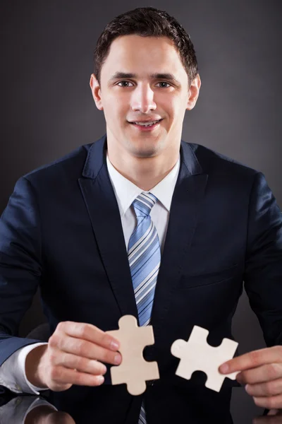 Sonriente hombre de negocios uniéndose a piezas de rompecabezas —  Fotos de Stock