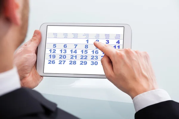 Деловой человек касаясь даты календаря на цифровой планшет в офисе — стоковое фото