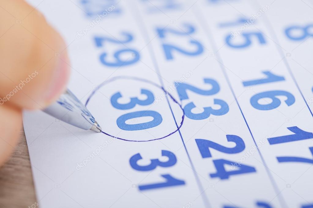 Businessman Marking Date On Calendar At Desk