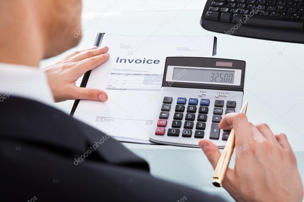 Businessman Calculating Invoice At Office Desk