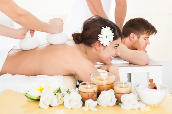 Mujer recibiendo masaje con compresas de hierbas sellos —  Fotos de Stock
