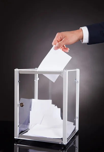 Empresario insertando papeleta en caja — Foto de Stock