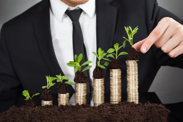 Empresario apilando arbolitos en monedas — Foto de Stock