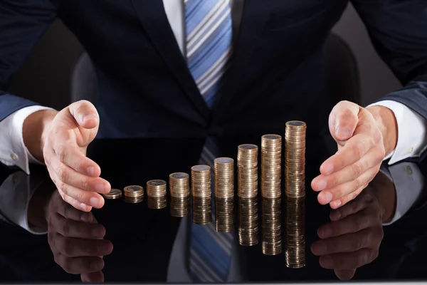 Die Hand des Geschäftsmannes schützt Münzen am Schreibtisch — Stockfoto