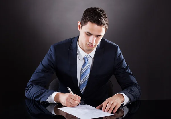 Jungunternehmer unterschreibt Vertrag am Schreibtisch — Stockfoto