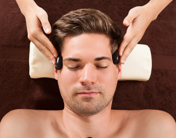 Hombre guapo recibiendo terapia de piedra caliente en spa —  Fotos de Stock