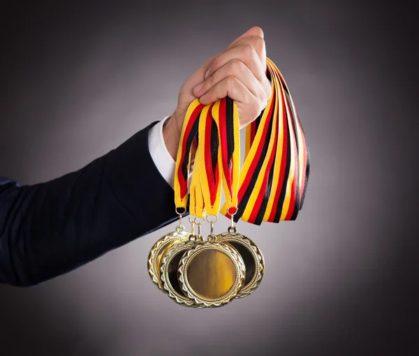 Businessman Holding Gold Medals — Stock Photo, Image