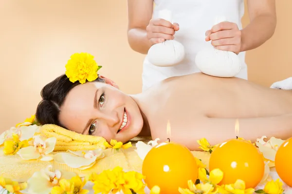 Vrouw ontvangende massage met kruiden comprimeren stempels in spa — Stockfoto