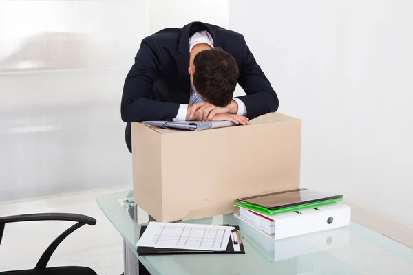 Empresario cansado descansando en la caja de cartón en el escritorio —  Fotos de Stock