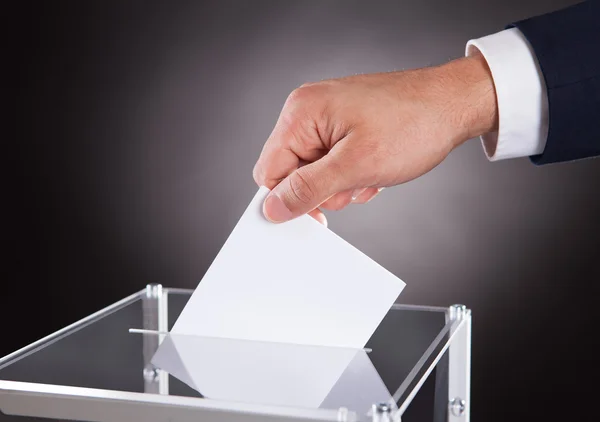 Empresario insertando papeleta en la caja en el escritorio —  Fotos de Stock