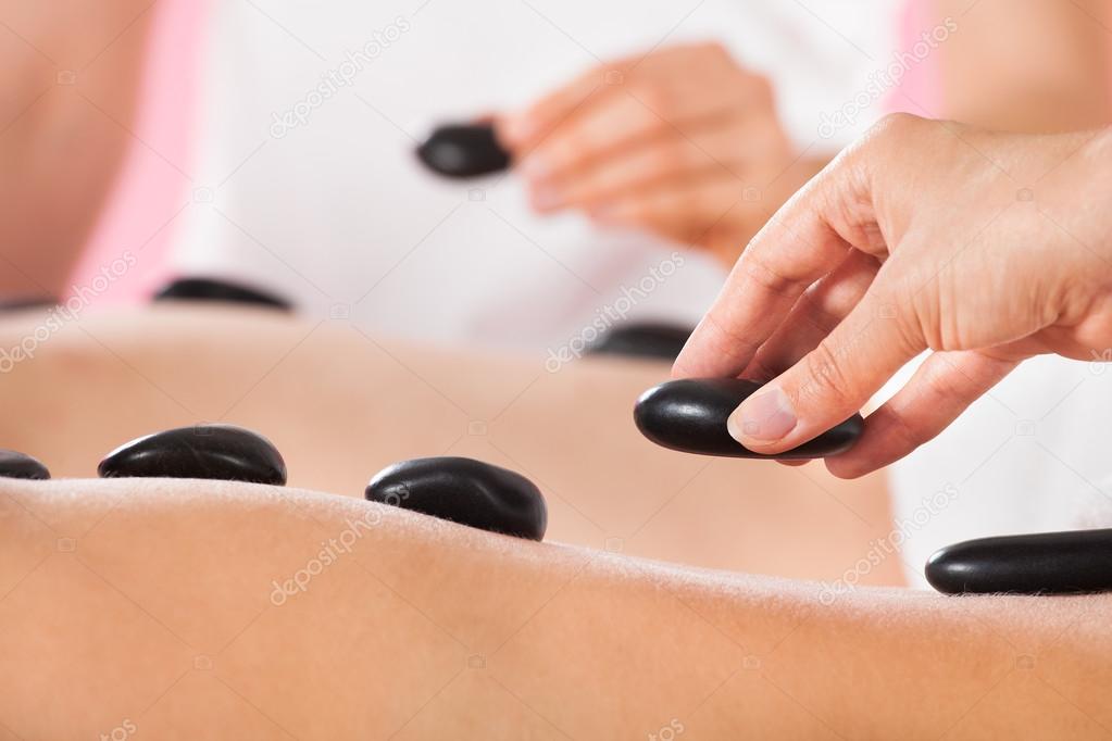 Couple Receiving Hot Stone Therapy At Spa