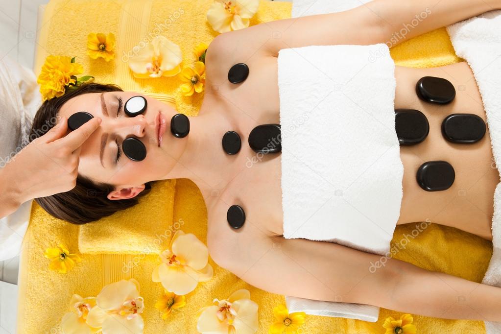 Relaxed Woman Receiving Hot Stone Therapy In Spa