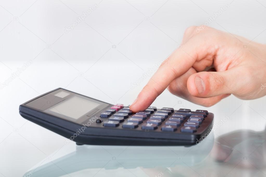 Businessman Using Calculator In Office