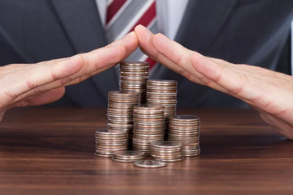 Businessman Sheltering Coin Stacks — Stock Photo, Image