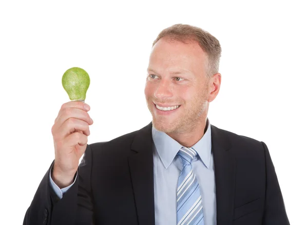 Uomo d'affari in possesso di lampadina verde — Foto Stock