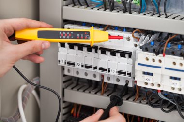 Electrician Examining Fusebox With Voltage Tester clipart