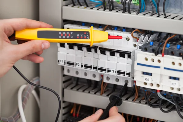 Eletricista examinando Fusebox com testador de tensão — Fotografia de Stock