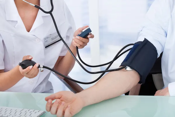 Médico verificando a pressão arterial — Fotografia de Stock