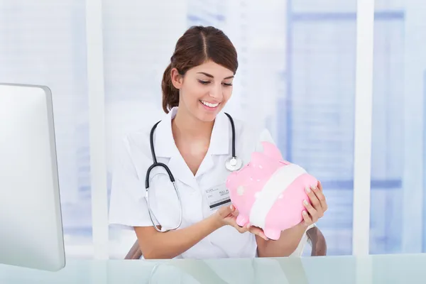 Médico mirando a Piggybank — Foto de Stock