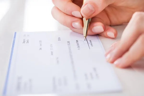 Zakenvrouw ondertekening van cheque — Stockfoto