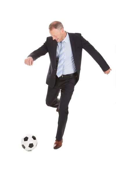Empresário chutando bola de futebol — Fotografia de Stock