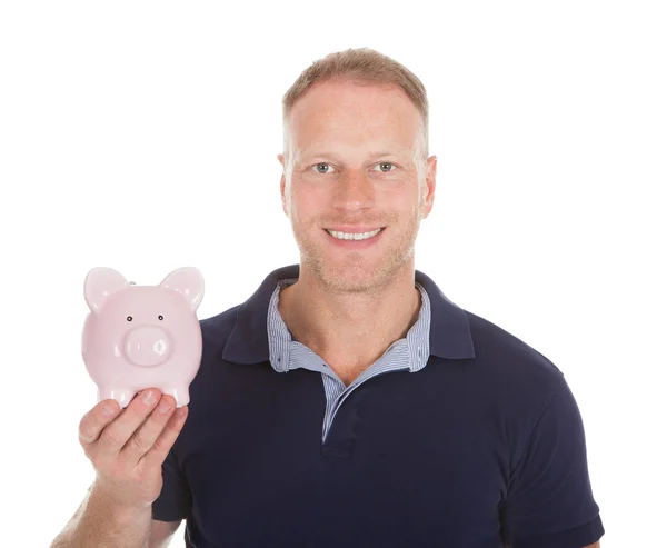 Homem jovem segurando Piggybank — Fotografia de Stock