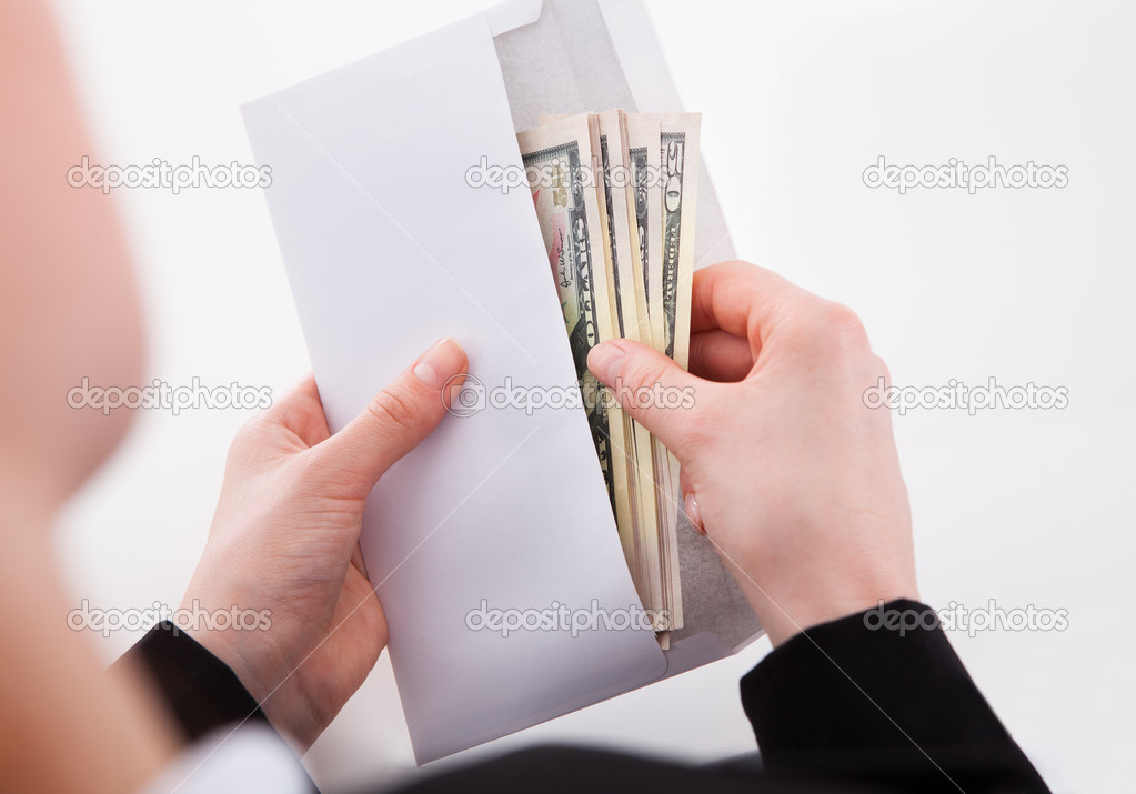 Businesswoman Putting dollars In Envelope