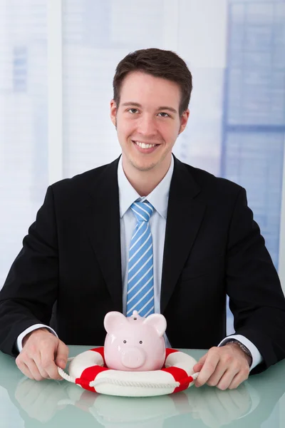 Affärsman skydda piggybank — Stockfoto