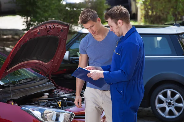 Mechanic Showing Clipboard to Customer — стоковое фото