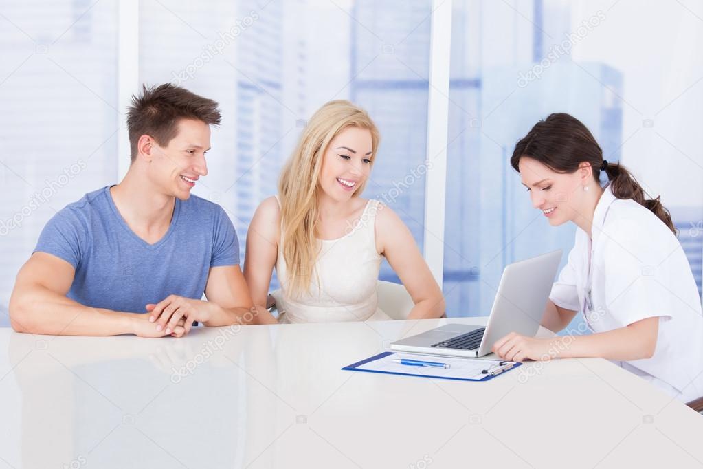 Doctor Showing Report On Laptop To Couple
