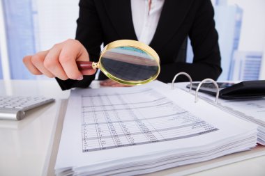 Businesswoman Scrutinizing Bills With Magnifying Glass clipart