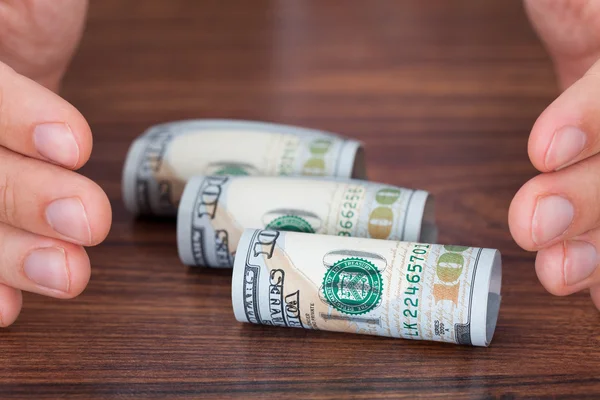 Manos protegiendo billetes de banco laminados —  Fotos de Stock