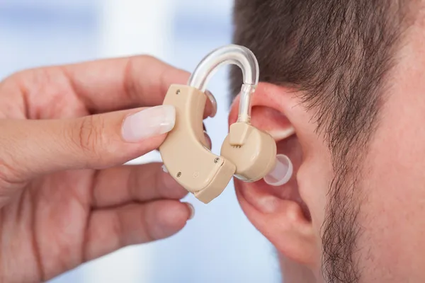 Médico que insere o aparelho auditivo — Fotografia de Stock